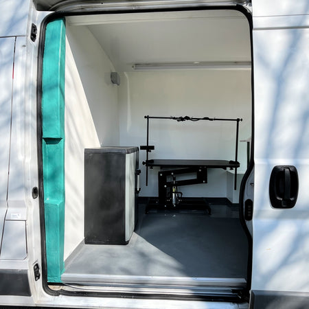 mobile dog grooming van with open door showing grooming table inside